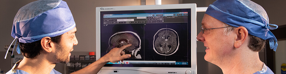 A pair of surgeons review the results of a scan on a screen