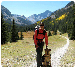 A woman walks her dogs on a mountainous trail